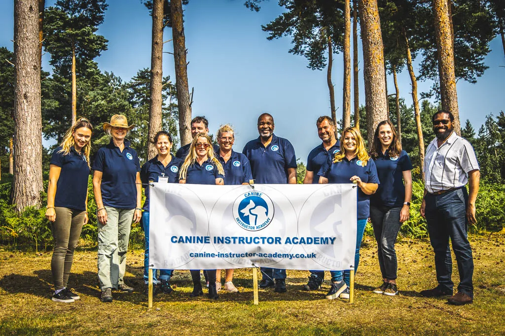 A group of people stood behind a canine instructor academy banner with Rob Alleyne